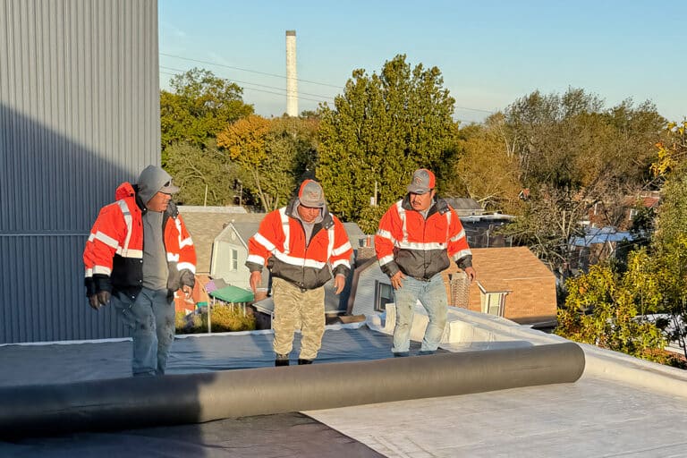 Meyers roofers unroll covering on commercial roof.