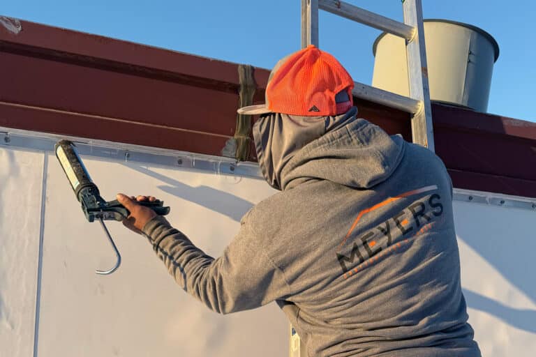 Worker caulks a seam on a flat roof.