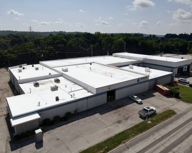 Aerial view of the Davlan Engineering building with a large white flat roof, rooftop HVAC units, and trees behind.